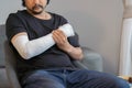 Man with arm and hand wrapped in medical bandage at home. First aid, treatment after accident injury Royalty Free Stock Photo