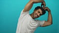 Man arm raises forming heart gesture in bright turquoise studio with fingertips touching overhead; affection joy Royalty Free Stock Photo