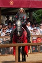man in armor riding on horse at horse show and people watching