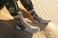 A man in army pants and lace-up boots sits in the desert Royalty Free Stock Photo