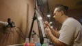 Man artist learns to paint with airbrush with acrylic dye, paper and easel. Concept modern art, airbrushing, aerography