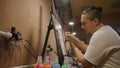 Man artist learns to paint with airbrush with acrylic dye, paper and easel. Concept modern art, airbrushing, aerography