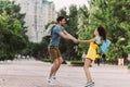 Man and asian woman smiling, jumping and holding hands