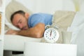 man asleep in bed alarm clock showing twelve oclock