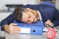 man asleep on folder in workplace