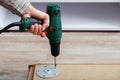 Man assembles table furniture with drill. Assembly, furniture repair home master. Male hand with drill on floor. Copy space