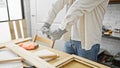 A man assembles wooden frames in a bright carpentry workshop, illustrating craftsmanship and manual labor Royalty Free Stock Photo