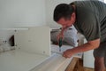 Man assembling furniture with power cordless screwdriver. He is improving his home with new computer desk. Royalty Free Stock Photo