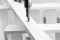 Man assembling a white flat pack ladder shelving unit with a screwdriver.