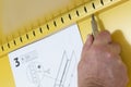 Man assembling a yellow metal cabinet with a screwdriver and instructions. Self assembly furniture concept