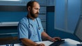 Man assistant sitting at desk typing medical expertise on computer