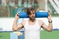 Man athlete with blue yoga mat in muscular hands