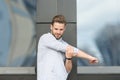 Man athlete concentrated face stretching arms before workout, urban background. Runner stretching training outdoor