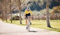 Man, athlete and cycling path in park, exercise and training of triathlon sports in sunshine. Cyclist, bicycle and ride