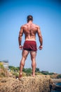 Man Athlete stands on a rock by the sea