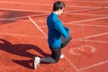 Man athlete on the starting line of a running track at the stadium, resting on his knees. Royalty Free Stock Photo