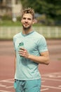 Man with athletic appearance holds bottle with water. Athlete drink water after training at stadium on sunny day. Sport Royalty Free Stock Photo