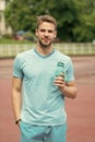 Man with athletic appearance holds bottle with water. Athlete drink water after training at stadium on sunny day. Man Royalty Free Stock Photo