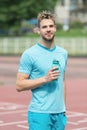 Man with athletic appearance holds bottle with water. Athlete drink water after training at stadium on sunny day. Sport Royalty Free Stock Photo