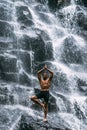 A man of athletic build does yoga. Healthy lifestyle. The concentration of the body. A man does yoga at a waterfall.