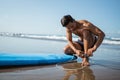 man attaches a safety harness to connect his feet to a surfboard