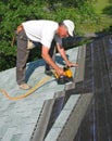 Man attaches shingles to roof