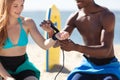 man attaching bodyboard strap to womans wrist