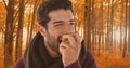 Man in Autumn eating apple in forest Royalty Free Stock Photo