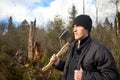 Man with an axe looks at the tumbled down wood