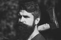 Man with axe outdoor. Handsome man hipster or guy with beard and moustache on serious face. Royalty Free Stock Photo