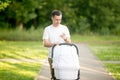 Man with baby carriage in park looking at phone screen Royalty Free Stock Photo