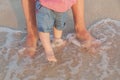 Man and baby feet standing in shallow water waiting for the wave. Bare feet father and his little daughter or son Royalty Free Stock Photo