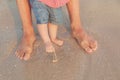 Man and baby feet standing in shallow water waiting for the wave. Bare feet father and his little daughter or son Royalty Free Stock Photo