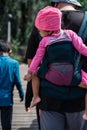 Man with a baby in a sling behind his back walking with the children