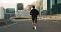 Man, back and running in morning on city, street and bridge for fitness, workout and marathon training. Athlete, person