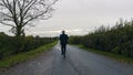 A man with back to the camera, walking down a country lane in winter Royalty Free Stock Photo