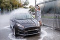 The man in the background has raised the water cannon above his head and is aiming it at the roof of the auto. A car at a self Royalty Free Stock Photo