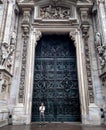 man on the background of a huge door to the dumo cathedral in Milan Italy