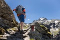 A man with a backpack climbs a mountain path and leans on a rock, Austria, the Alps