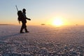 The man with a backpack going on ice on the river at sunset Royalty Free Stock Photo