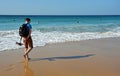 Man with backpack and hanging shoes walking on amazing beach in El Cotillo