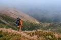 A man with a backpack for a hike climbs to the top of the mountain on a rocky path, a tourist hike in the Carpathians in Royalty Free Stock Photo