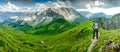 Hiker Man on Hiking Trail with Backpack standing relaxed and enjoying panoramic view to mountains. Alps, Hohe Gaenge