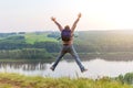 Man with a backpack jumping up on a hill. Royalty Free Stock Photo