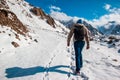 A man with a backpack makes a climb in the mountains. Deep marks in the snow
