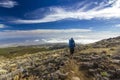 Man with backpack on path in semidesert with stones and blue sky