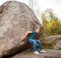 Man with backpack pushing a huge stone