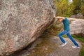 Man with backpack pushing a huge stone