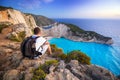 Man with backpack sitting watching sunset over Navagio beach on Zakynthos Royalty Free Stock Photo