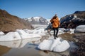 Man with a backpack standing on a background of glacier, icebergs and snow-capped mountains. Landscape with man, rocks